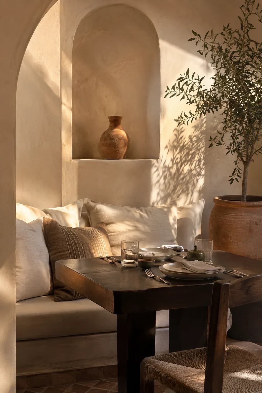Sun-warmed plaster alcove with linen cushions and a low dining table